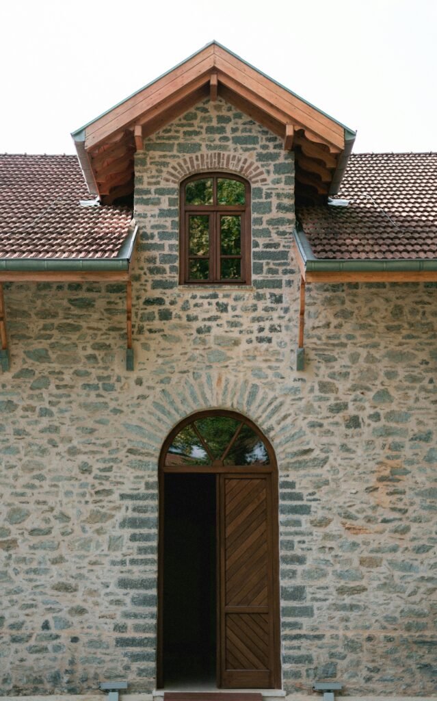Charming stone house exterior with wooden door ajar, classic rustic style.